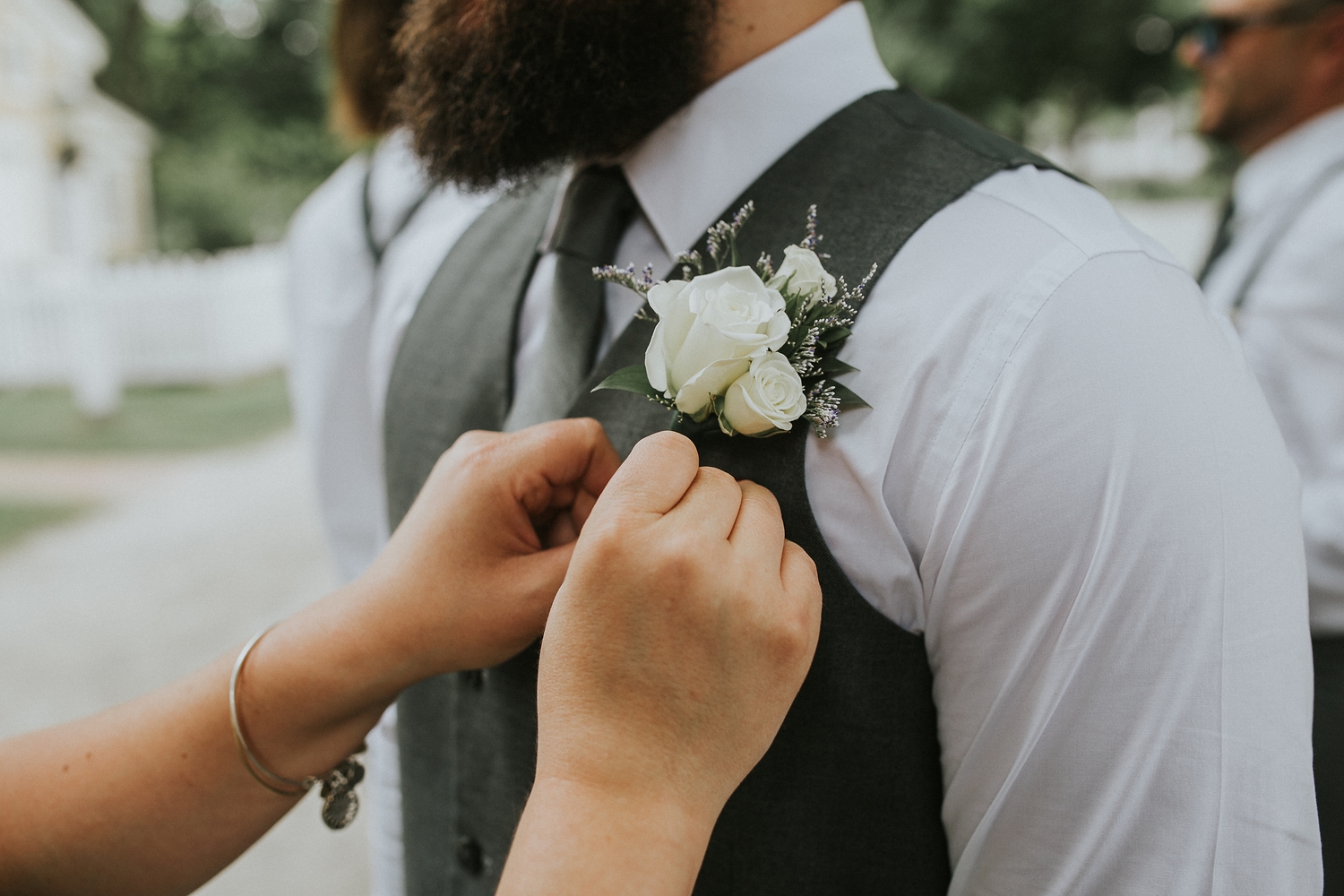 Boutonniere being pinned to the groom's vest