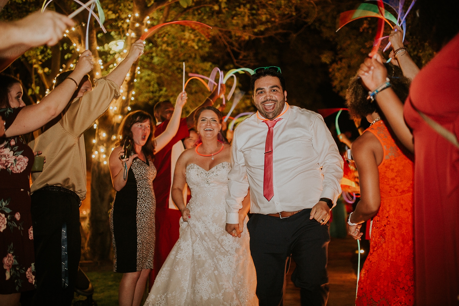 Couple leaving through a tunnel of glow sticks