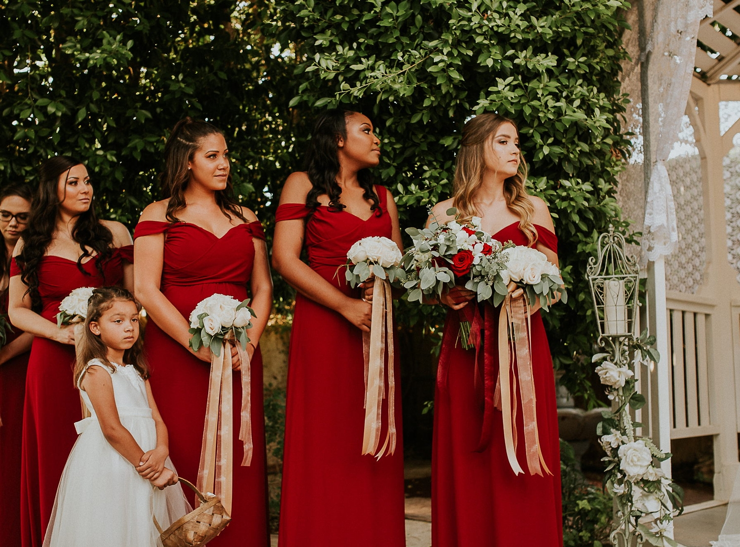 Bridesmaids in red beside a flower girl