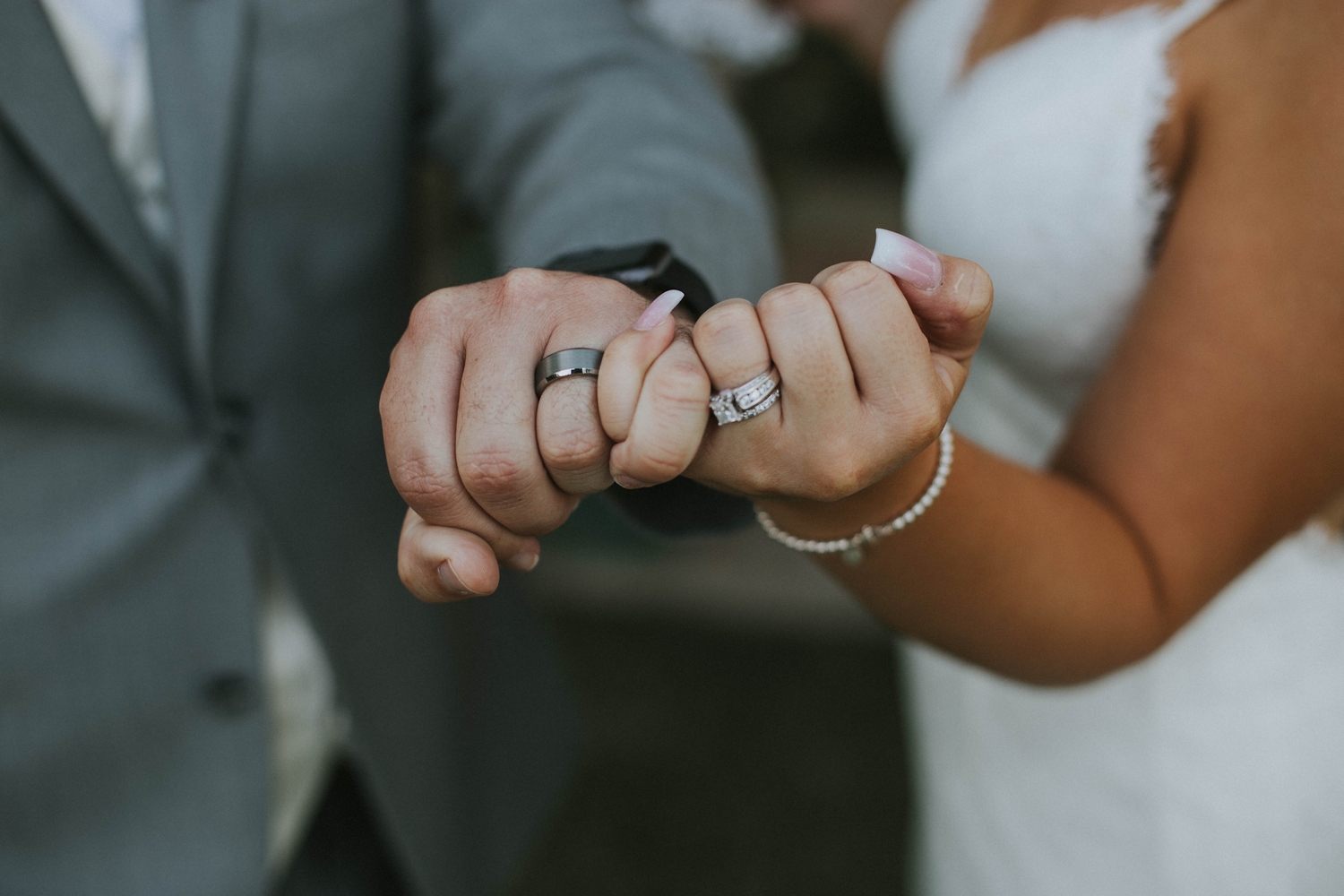 Couple linking pinkies to show their rings